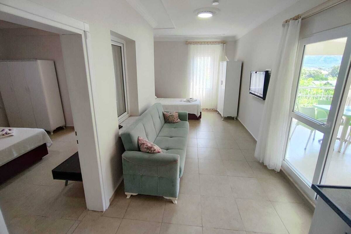 A spacious living area with a sofa, a small table, and a TV mounted on the wall.