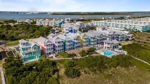 Un quartier résidentiel situé sur la côte, avec des maisons aux couleurs vives, une piscine et une vue sur l’océan.