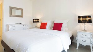 Una habitación de hotel con una cama grande, dos mesitas de noche, un espejo y dos lámparas.