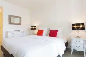 Una habitación de hotel con una cama grande, dos mesitas de noche, un espejo y dos lámparas.