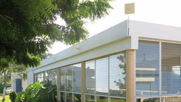 A modern house with large glass windows, a flat roof, and a garden with various plants. - Casa Bakab by Rotamundos (Mérida)