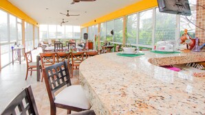 A spacious dining area with a granite countertop, multiple ceiling fans, and large windows offering a view of the outdoors. - Casa Bakab by Rotamundos (Mérida)