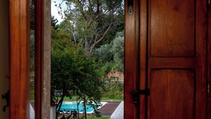 Uma porta de madeira dá para um quintal com piscina e um caminho de pedra.