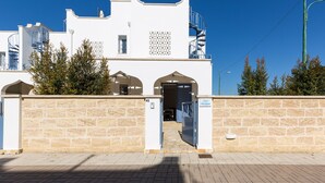 Een wit gebouw met een stenen muur, een wenteltrap en een heldere lucht.