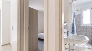 Een moderne badkamer met een groot wastafel, een douche en een betegelde wand.