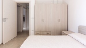Een slaapkamer met een bed, een kledingkast en een nachtkastje.