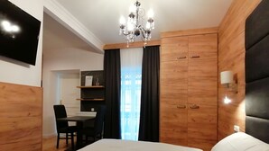 Quarto com cama, escrivaninha, cadeira, lustre e paredes de madeira.