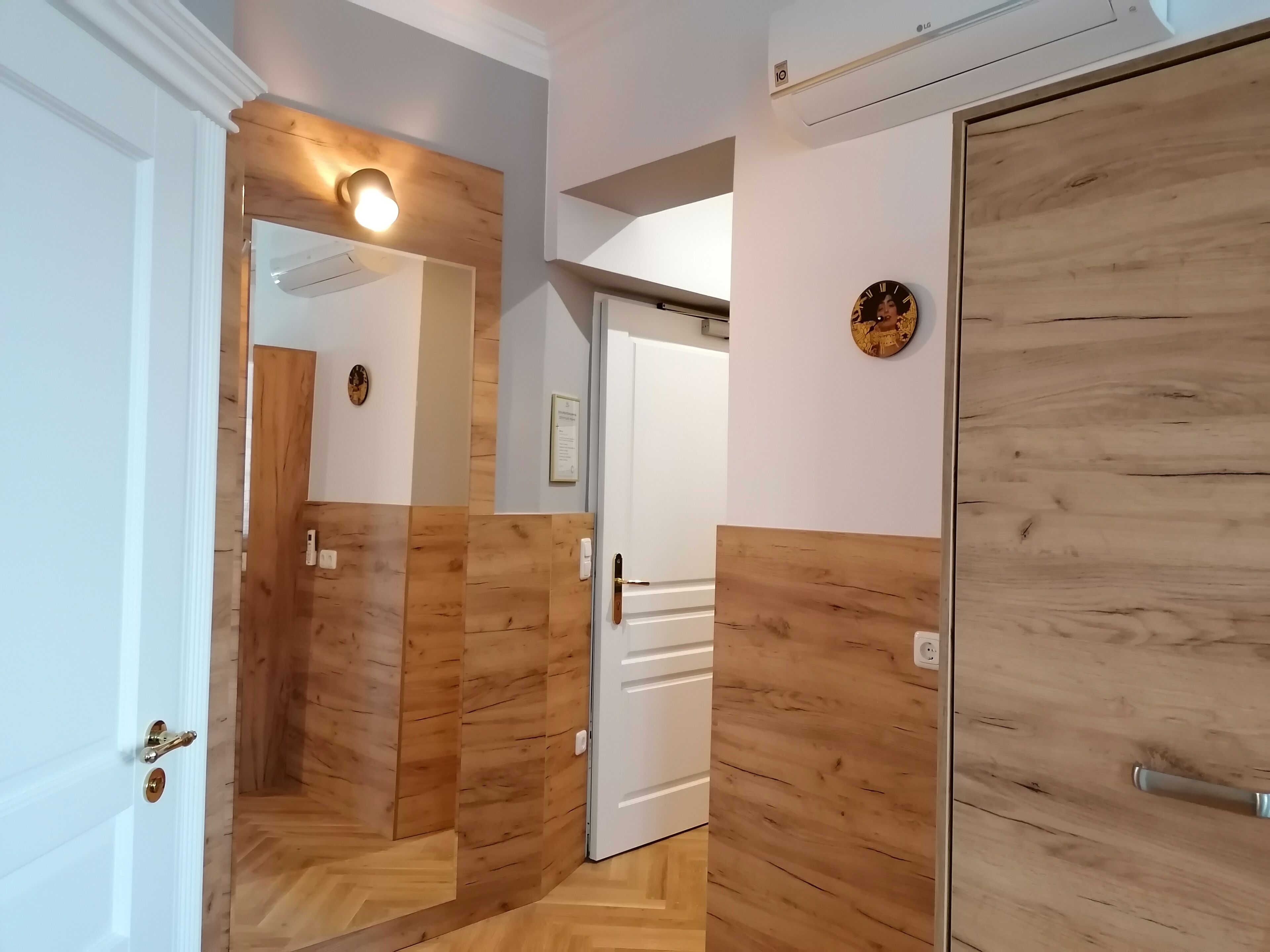 Un couloir aux murs recouverts de lambris en bois et une porte blanche.