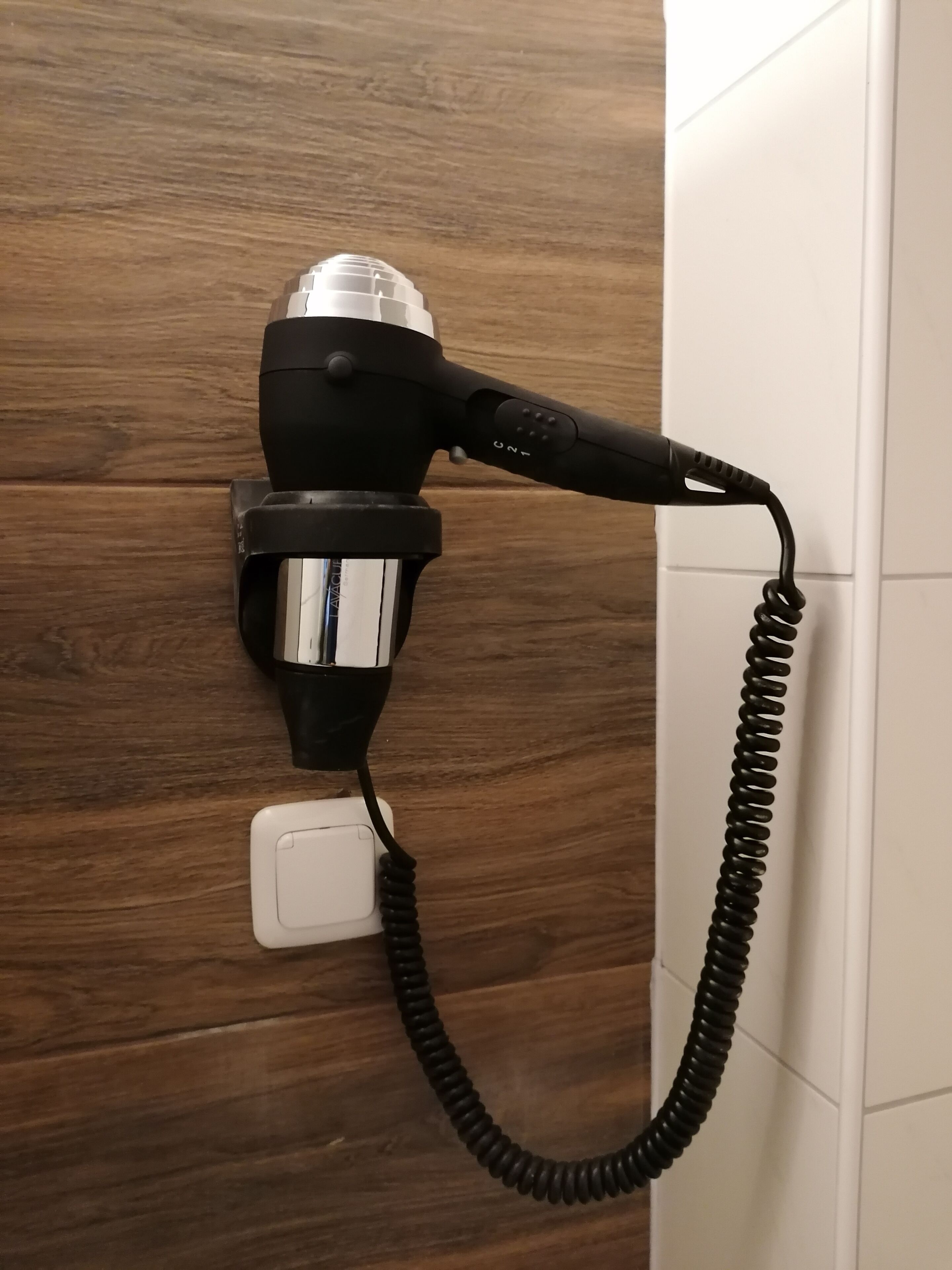 A hair dryer plugged into a wall socket.