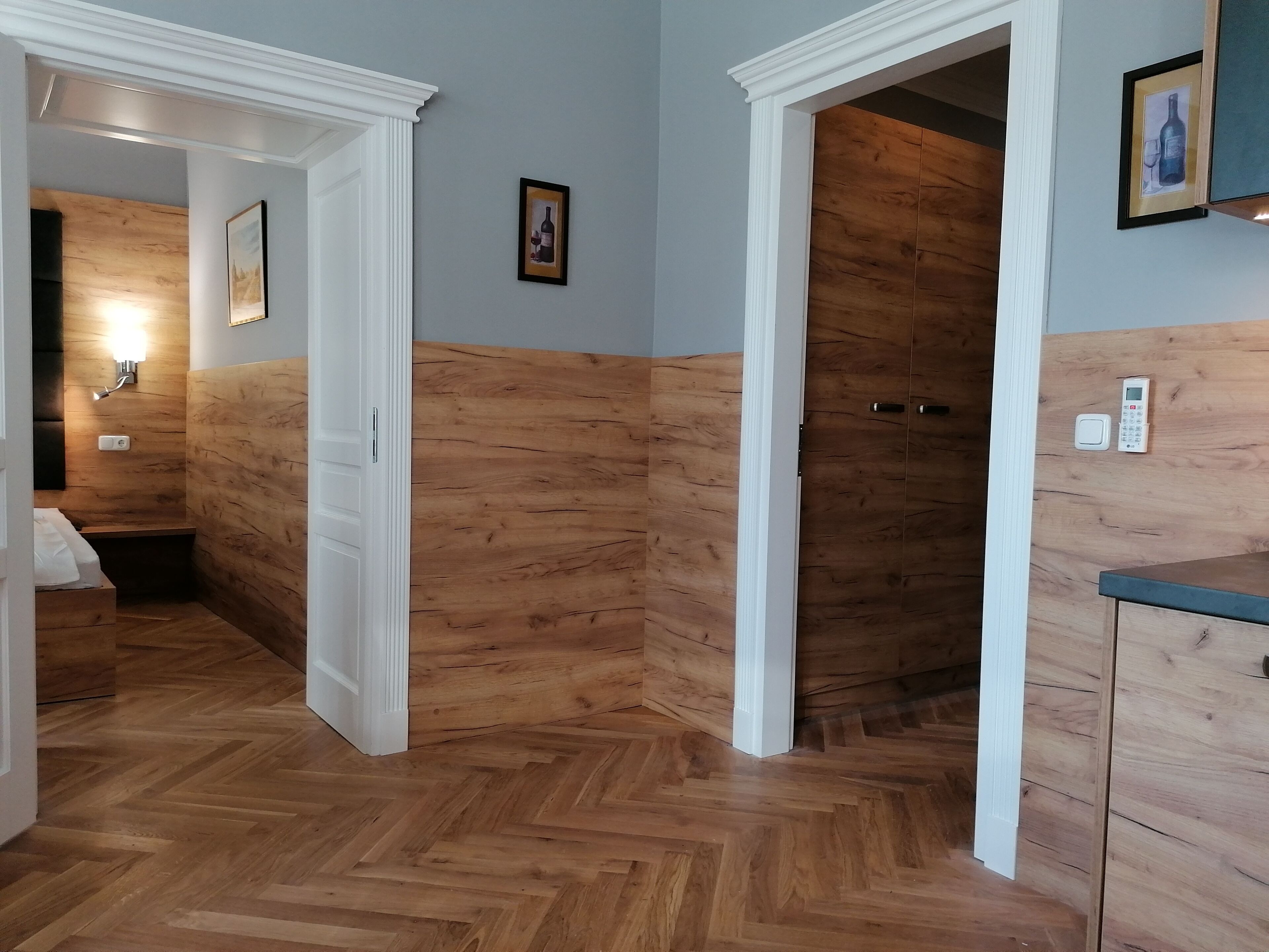 Ein Korridor mit Holzwandverkleidung, einer weißen Tür und einem kleinen gerahmten Bild an der Wand.