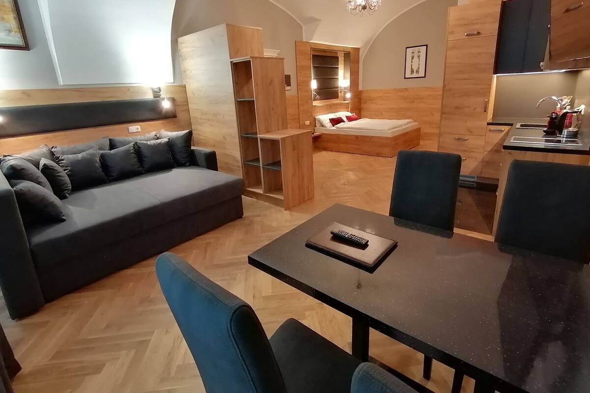 A modern living room with a sofa, dining table, and kitchen area.