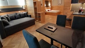 Uma sala de estar moderna com sofá, mesa de jantar e área de cozinha.