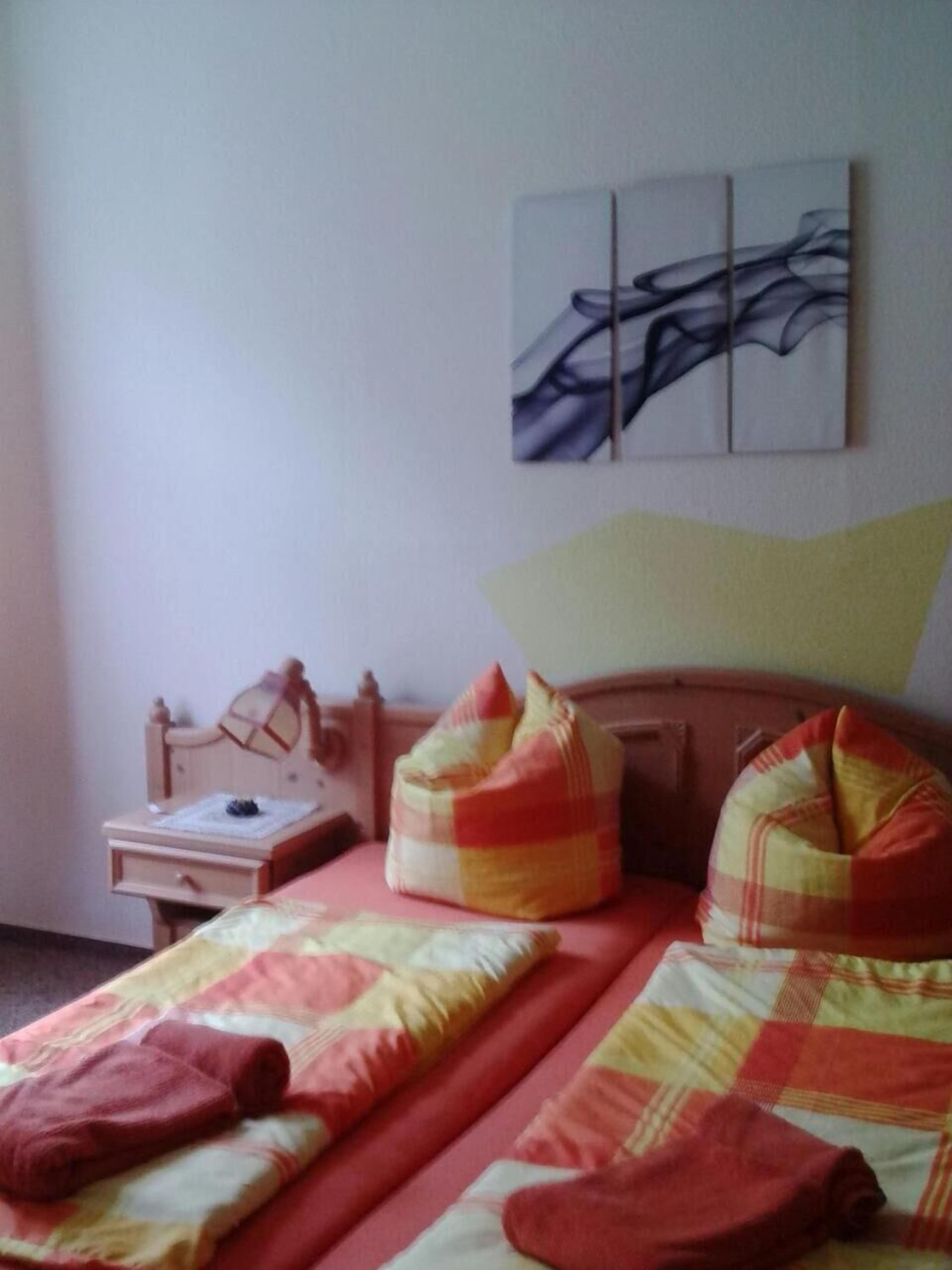 A bedroom with a bed, pillows, a nightstand, and a wall art piece.