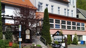 Um edifício de dois andares com telhado de telhas vermelhas, uma placa indicando um restaurante e uma motocicleta estacionada na frente.