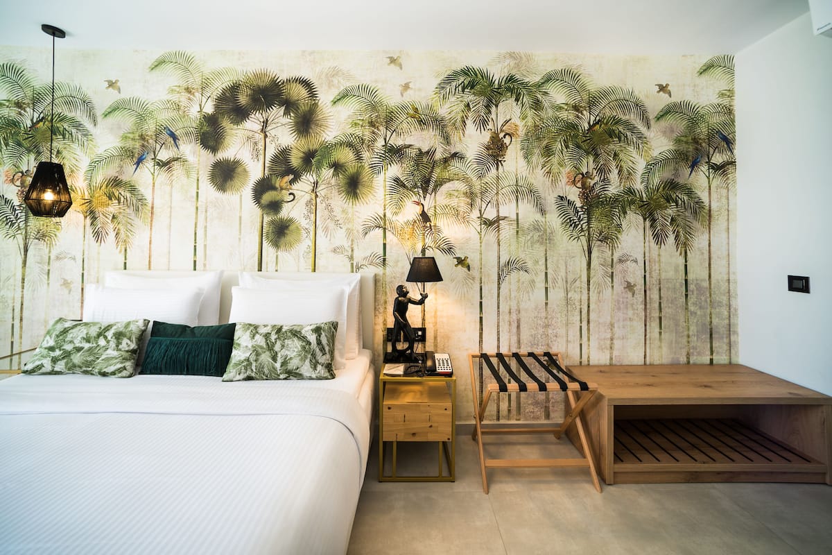 Quarto com cama, mesas de cabeceira, abajur e um banco de madeira.
