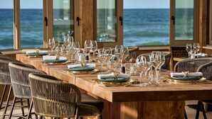A dining table set for a meal with a view of the ocean.