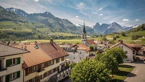 A town with traditional architecture, a prominent church, and a mountainous backdrop. - Auberge de l'Ange (Haut-Intyamon)