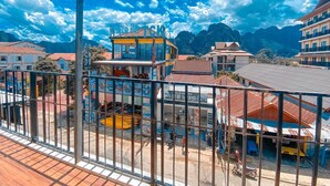 A balcony with a view of a mountain range and a building with a sign that reads "TCK". - Vang Vieng Freedom View - Hostel (Vang Vieng)