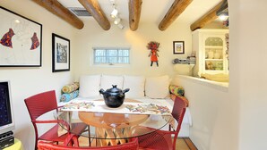 A cozy dining area with a round table, red wicker chairs, a black pot, and a white tablecloth. - Casa Archuleta | Charming Historic (Santa Fe)