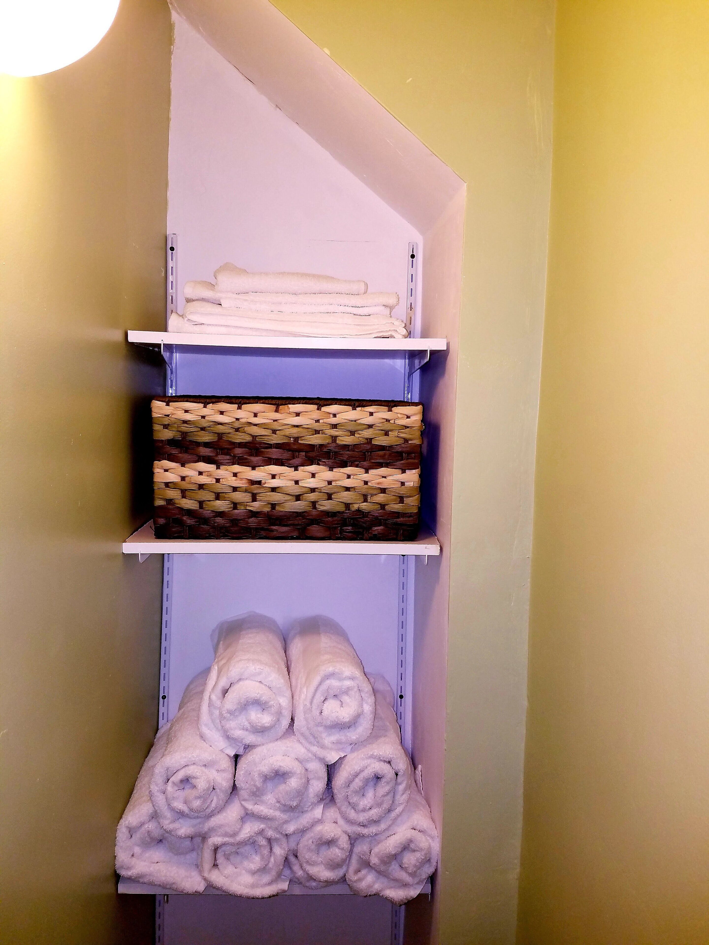 A storage shelf with folded towels and a woven basket.