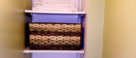 Un estante con toallas dobladas y una cesta tejida.
