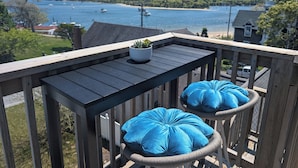 A balcony with a view of a lake, a potted plant, and two blue cushions. - The SandDollar Suite - Private Deck with Gorgeous Views of Onset Beach (Onset)