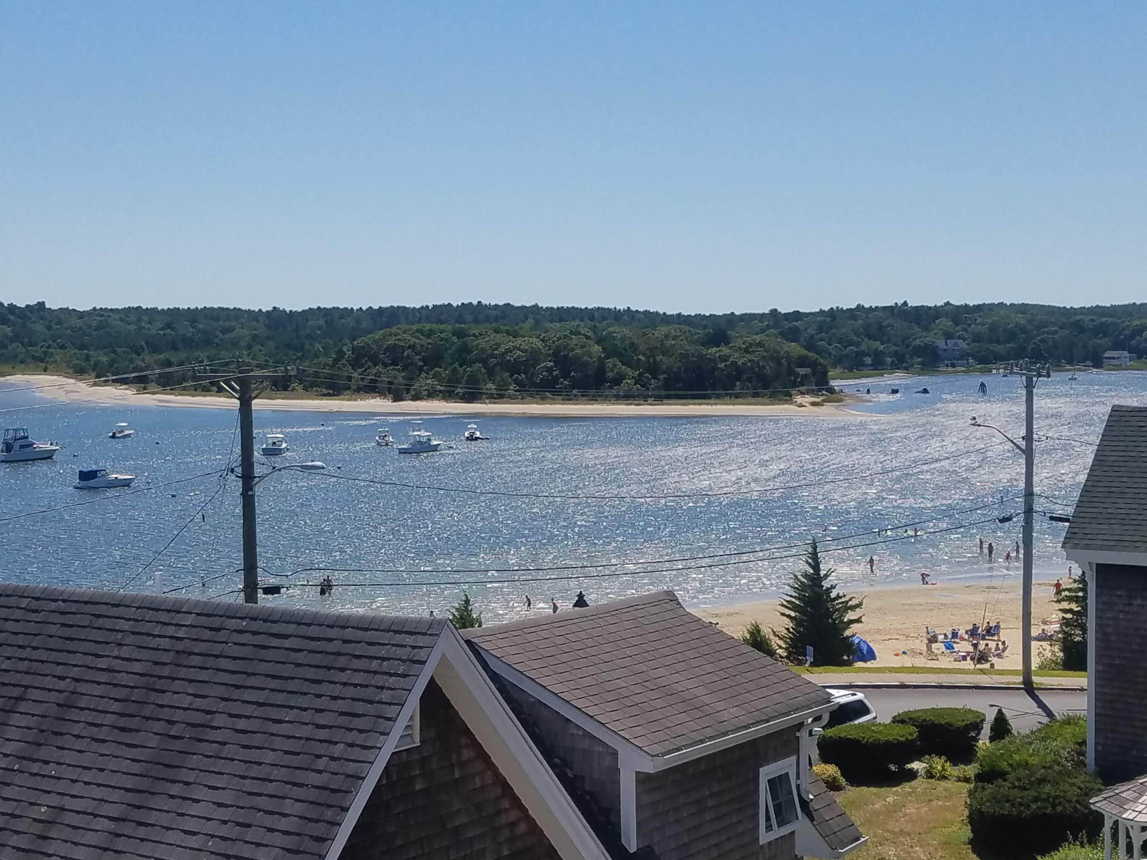 Vista costera con barcos en el agua, una playa y edificios residenciales.