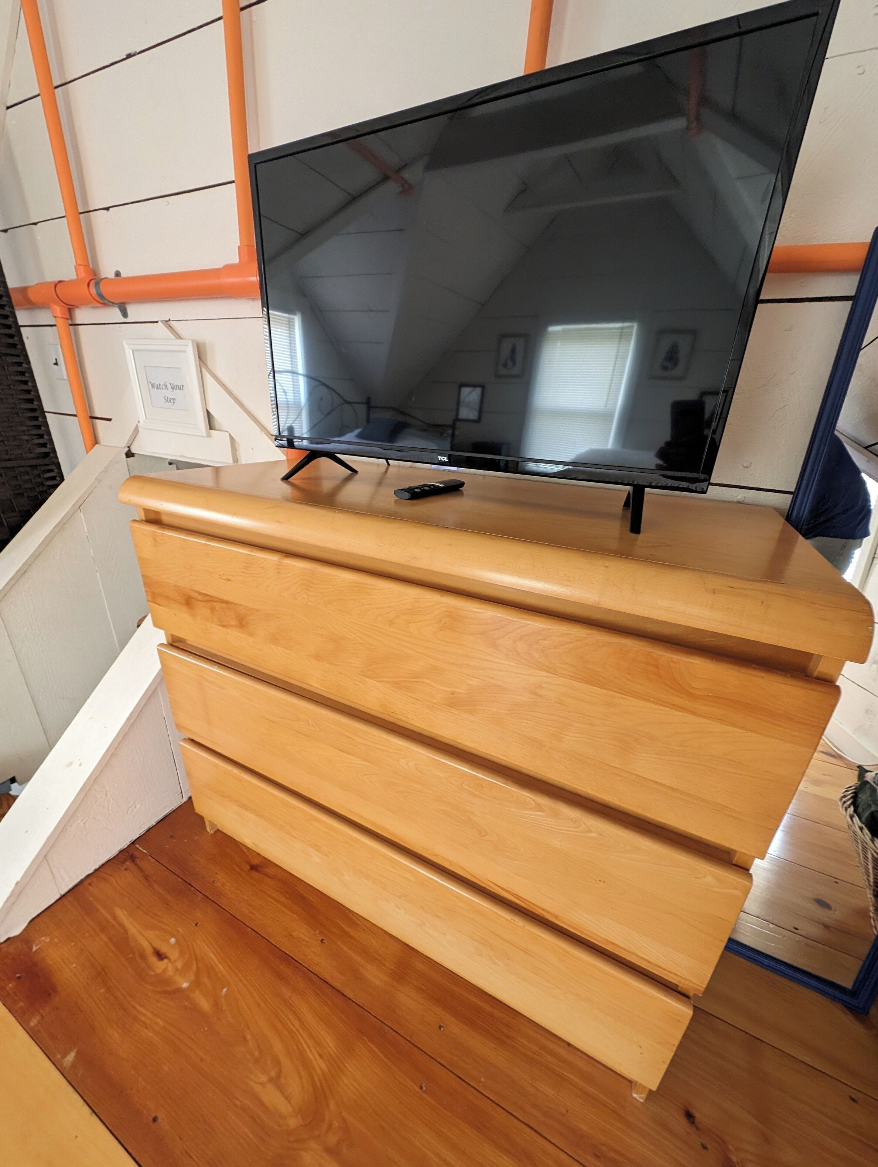 A wooden dresser with a flat-screen TV on top.