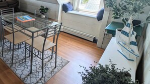 A cozy attic room with a dining table, chairs, and a window overlooking greenery. - The SandDollar Suite - Private Deck with Gorgeous Views of Onset Beach (Onset)