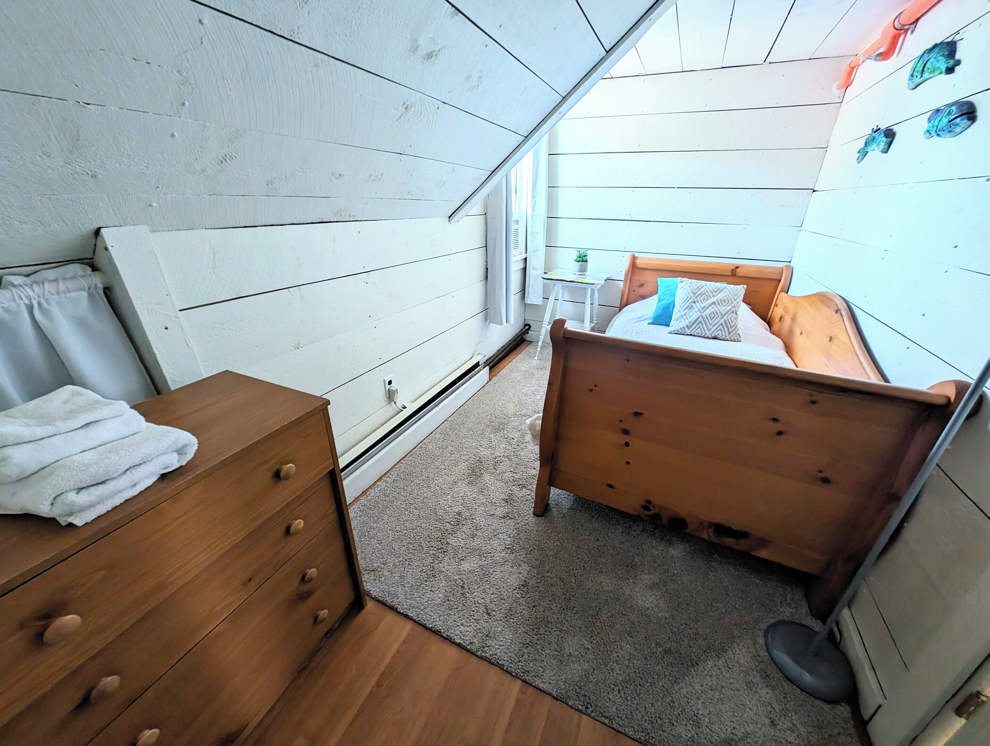 Un dormitorio con una cama de madera, un aparador de madera y una mesita con una planta.