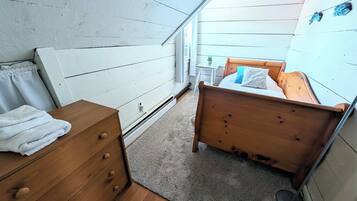 Un dormitorio con una cama de madera, un aparador de madera y una mesita con una planta.