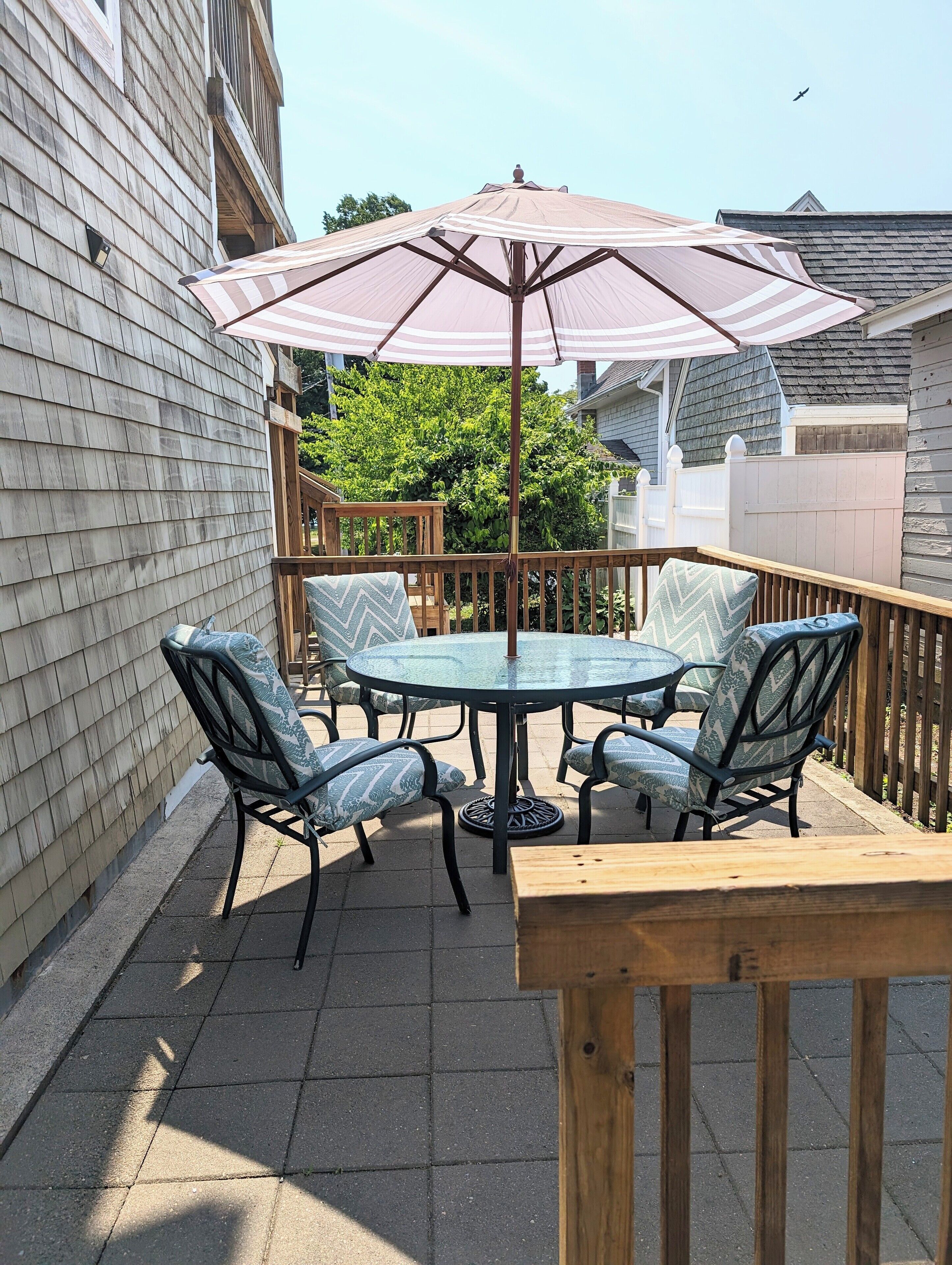 A patio with a round table and chairs, an umbrella, and a wooden deck.