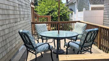 A patio with a round table and chairs, an umbrella, and a wooden deck.