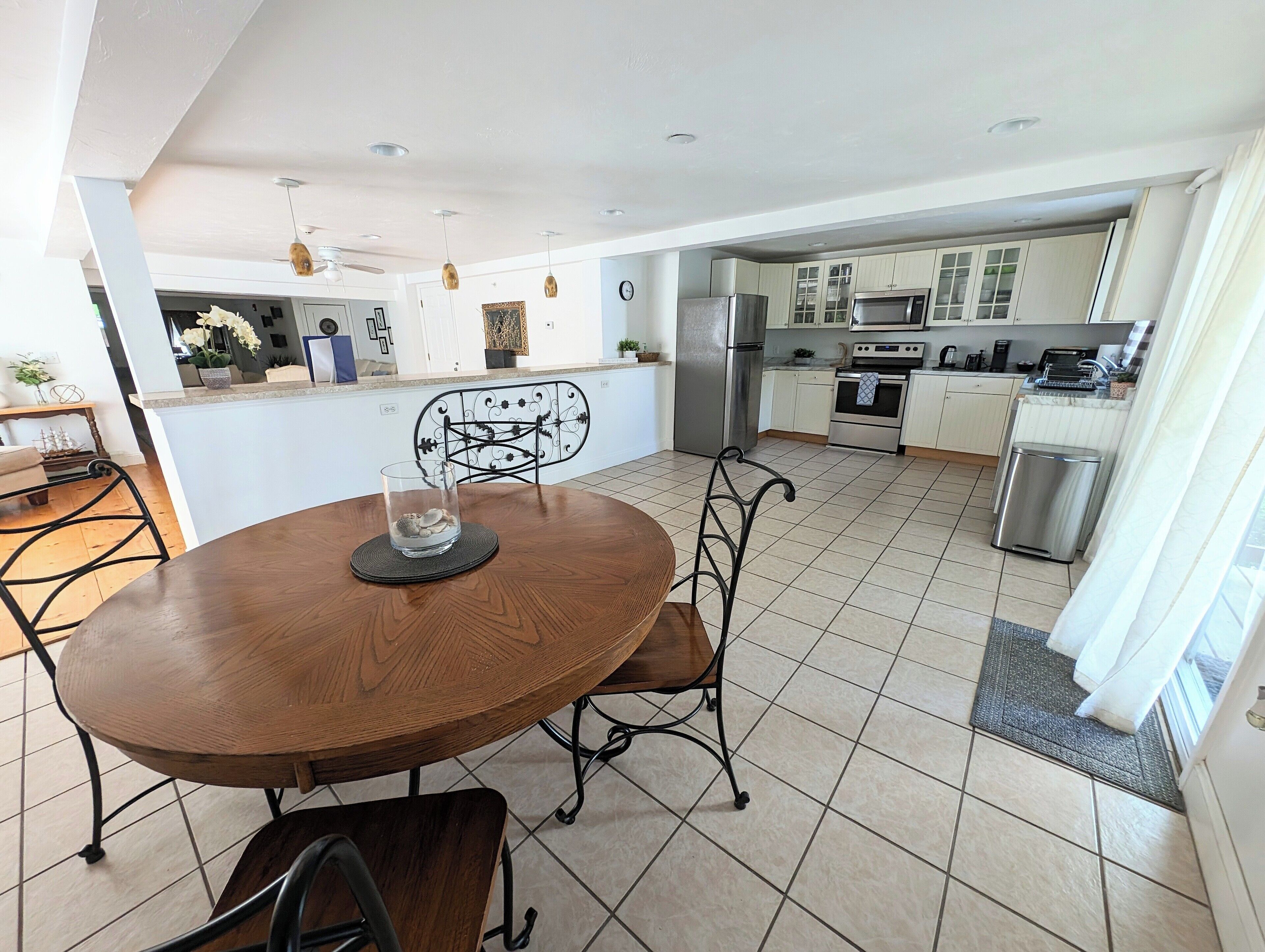 A modern kitchen with white cabinets, stainless steel appliances, and a dining area with a wooden table and metal chairs.