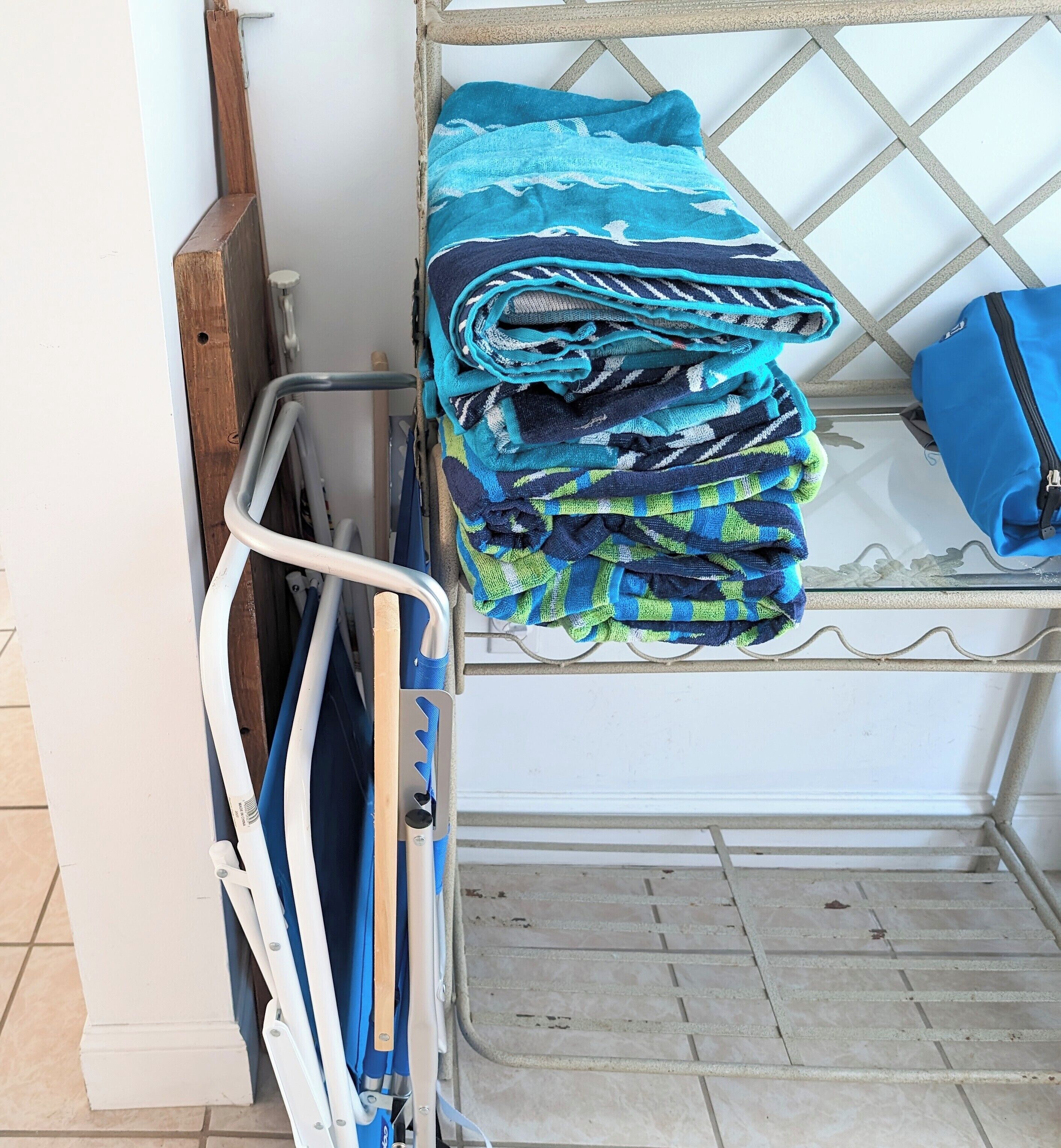 A metal rack with folded towels and a blue bag.