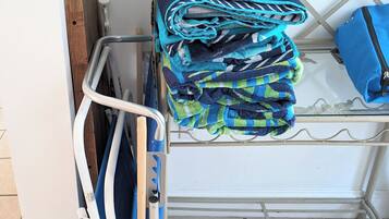 A metal rack with folded towels and a blue bag.