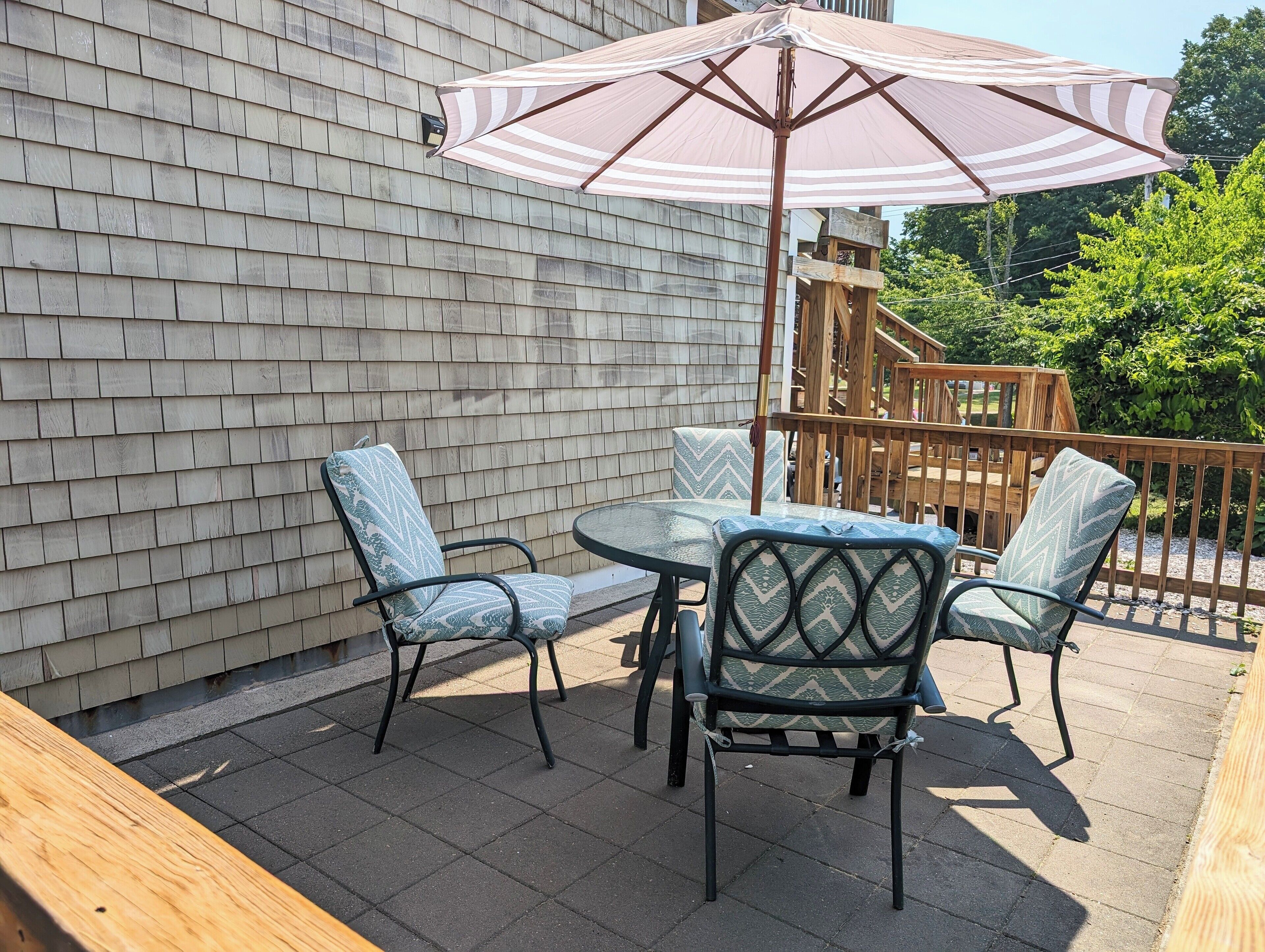 Une terrasse avec une table et quatre chaises, un parasol et une plateforme en bois.