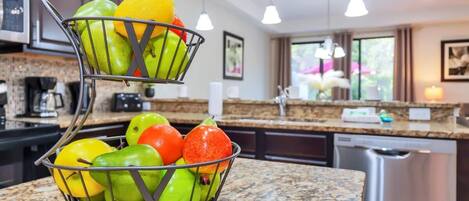A kitchen with a fruit basket on the counter, a microwave, and a dishwasher.