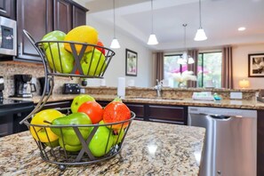 A kitchen with a fruit basket on the counter, a microwave, and a dishwasher.