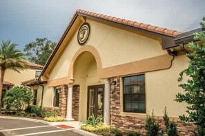 A building with a beige facade, a red-tiled roof, and a stone base. - Charming Townhome | Gated Resort with Pool (Davenport)