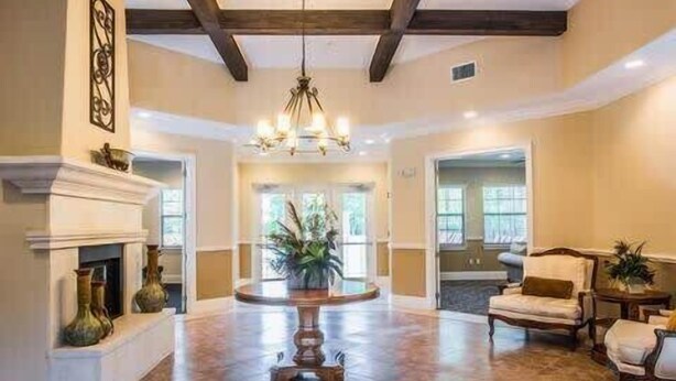 A spacious lobby with a fireplace, a chandelier, and a seating area with a table and chairs.