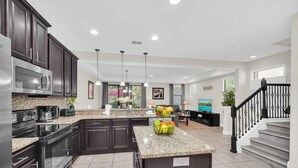 A modern kitchen with dark cabinets, stainless steel appliances, and granite countertops.