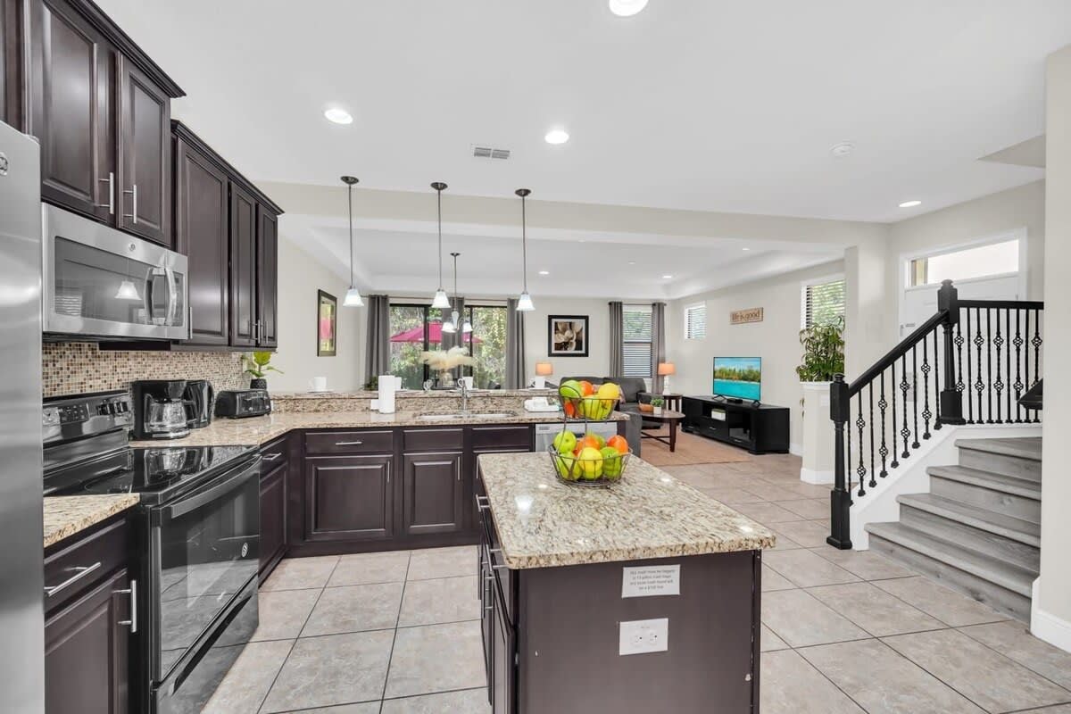 A modern kitchen with dark cabinetry, stainless steel appliances, and a granite countertop.