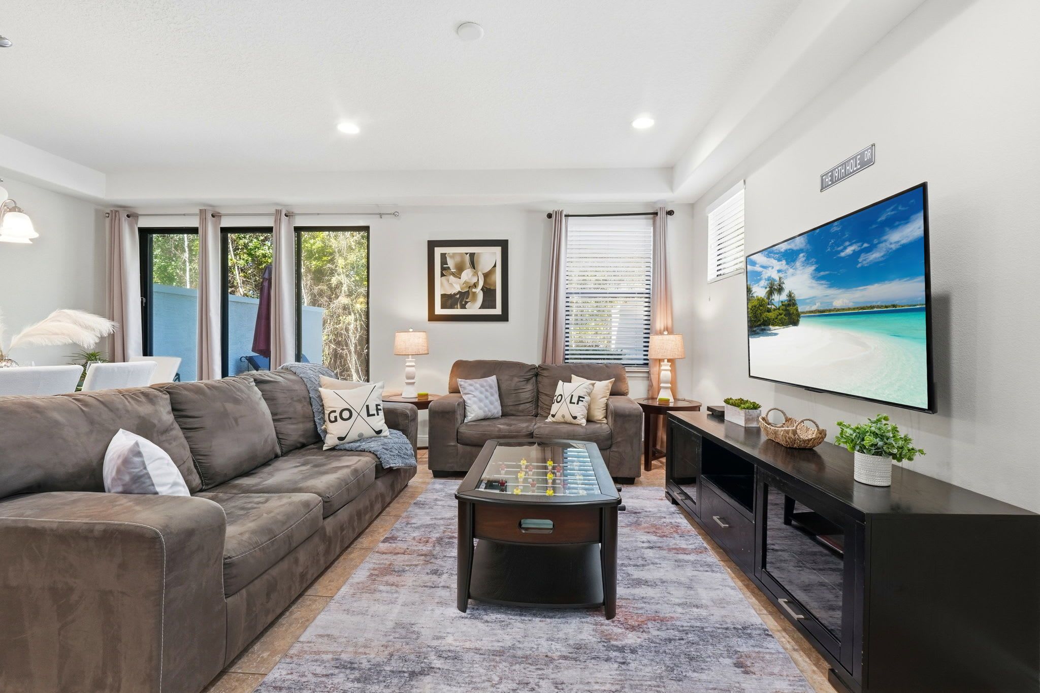 A modern living room with a sofa, coffee table, TV, and artwork.