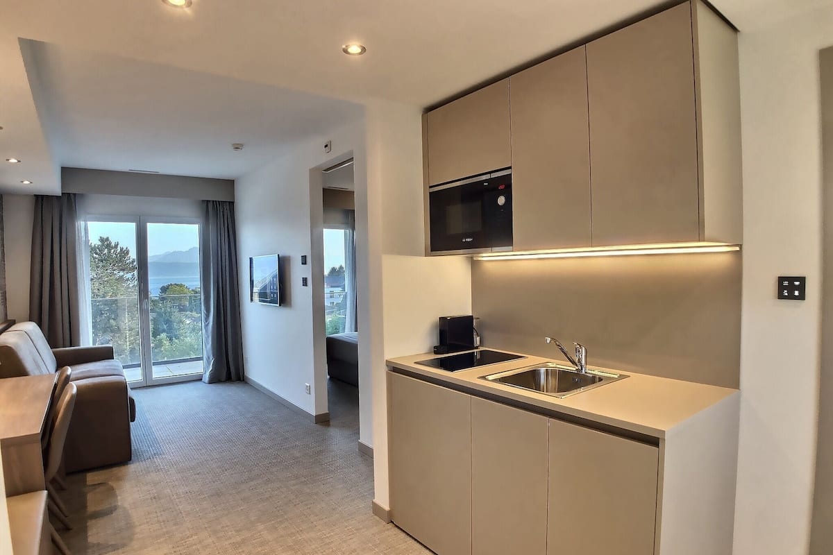 Una cocina moderna con microondas integrado, un lavamanos y una zona de comedor con sofá y mesa.