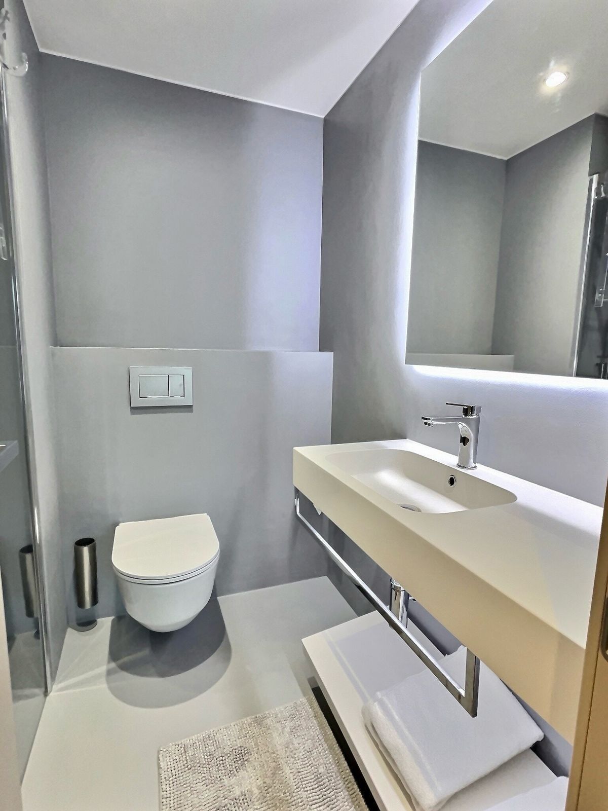 A modern bathroom with a toilet, sink, and mirror.