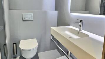 A modern bathroom with a toilet, sink, and mirror.