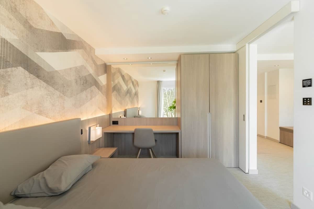Una habitación de hotel moderna con una cama, un escritorio y un espejo.