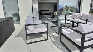 A modern outdoor seating area with white cushioned sofas and a black metal frame.