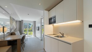 A modern kitchen with a built-in microwave, a stainless steel sink, and a dining area with a table and chairs.
